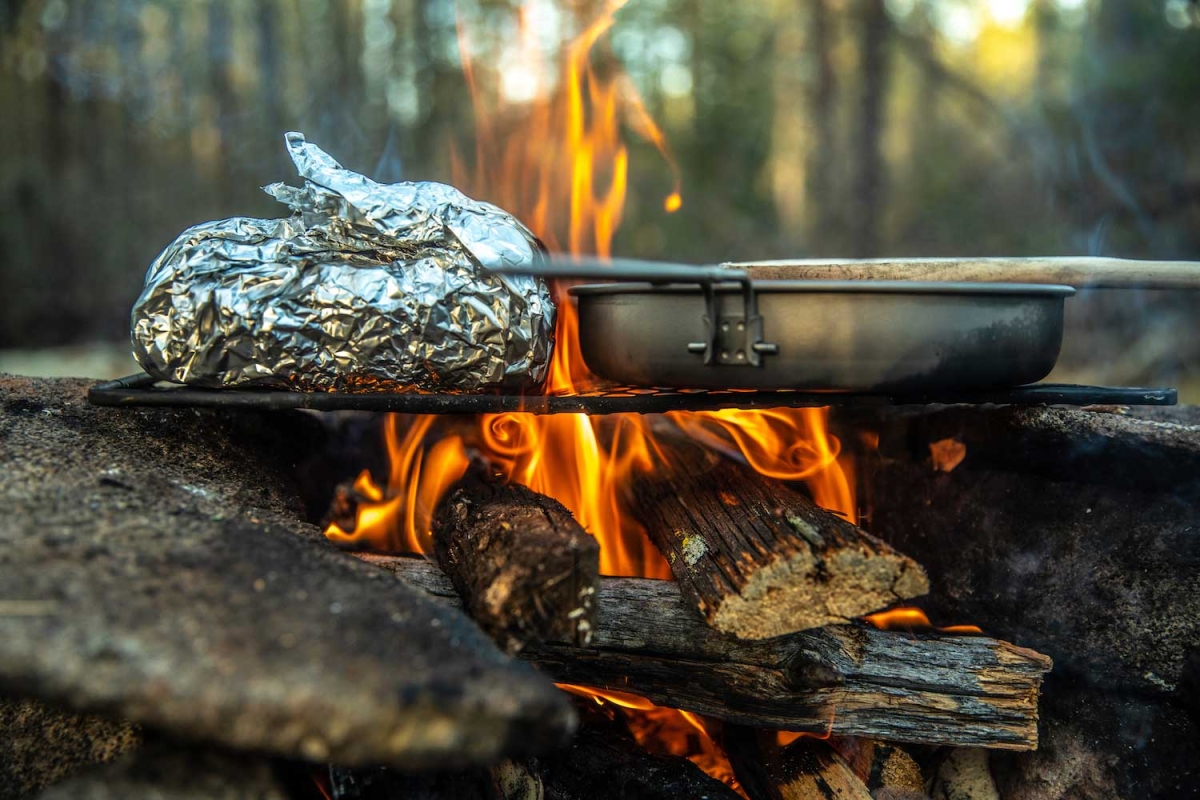 food wrapped in tin foil on skillet over an open fire 